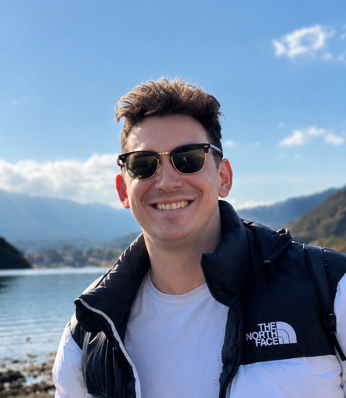 Daniel Leewood, founder of Leewood Consulting, smiling outdoors with mountains and a lake in the background.